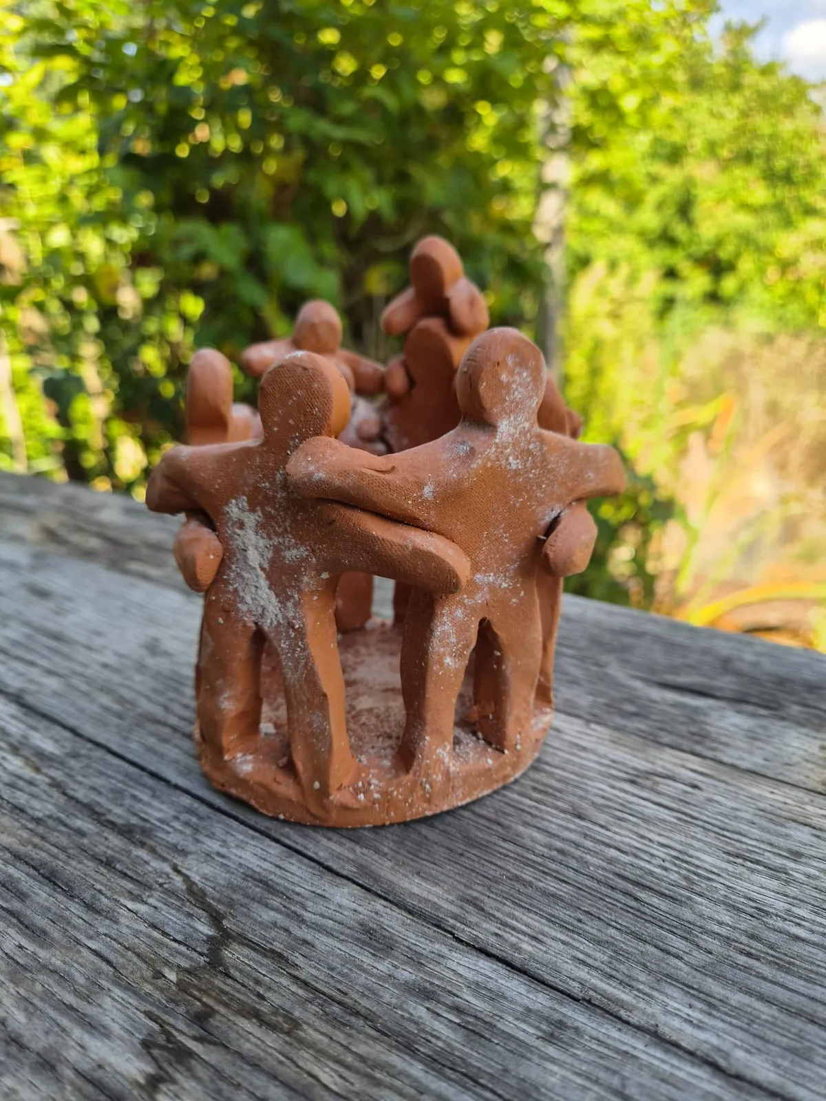 Beeldje van klei met figuren die elkaar vasthouden in een kring